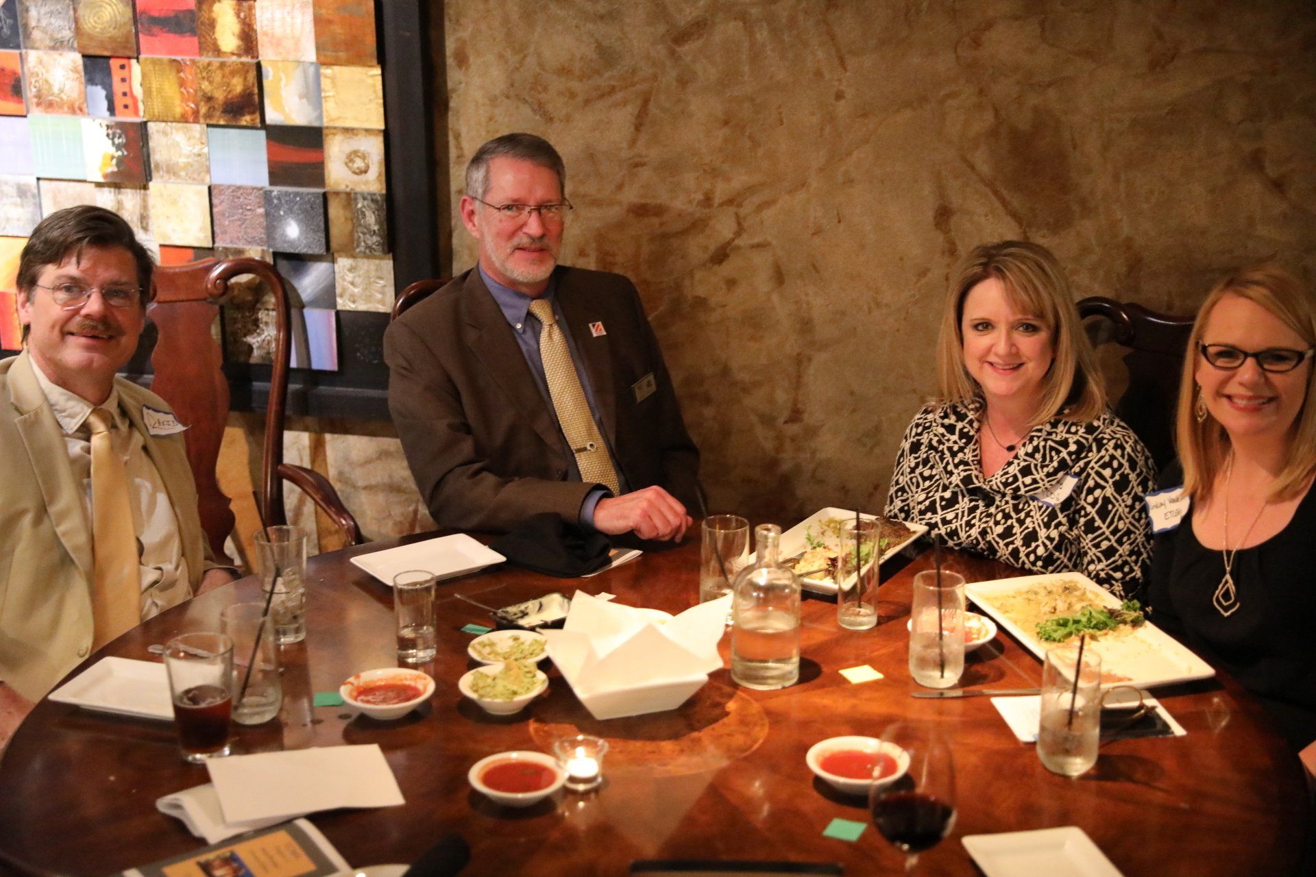 A group of people are sitting around a table with plates of food and drinks.