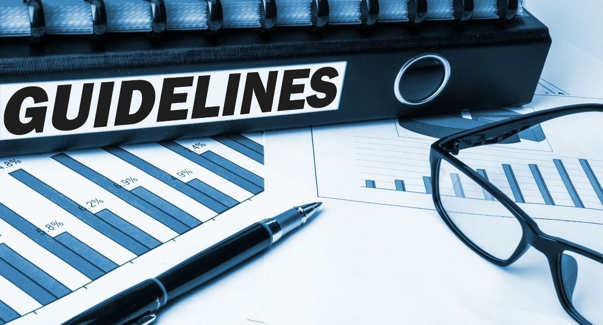 A pen and glasses are sitting on top of a binder with guidelines written on it.
