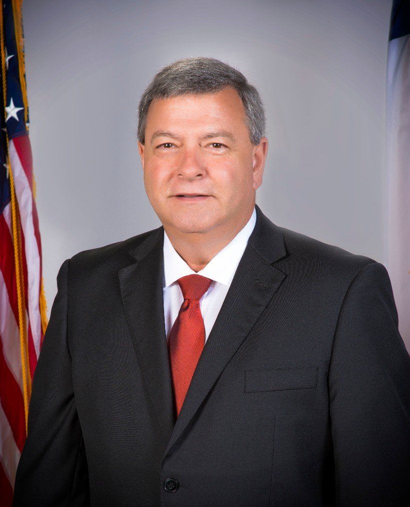 A man in a suit and tie is standing in front of an american flag