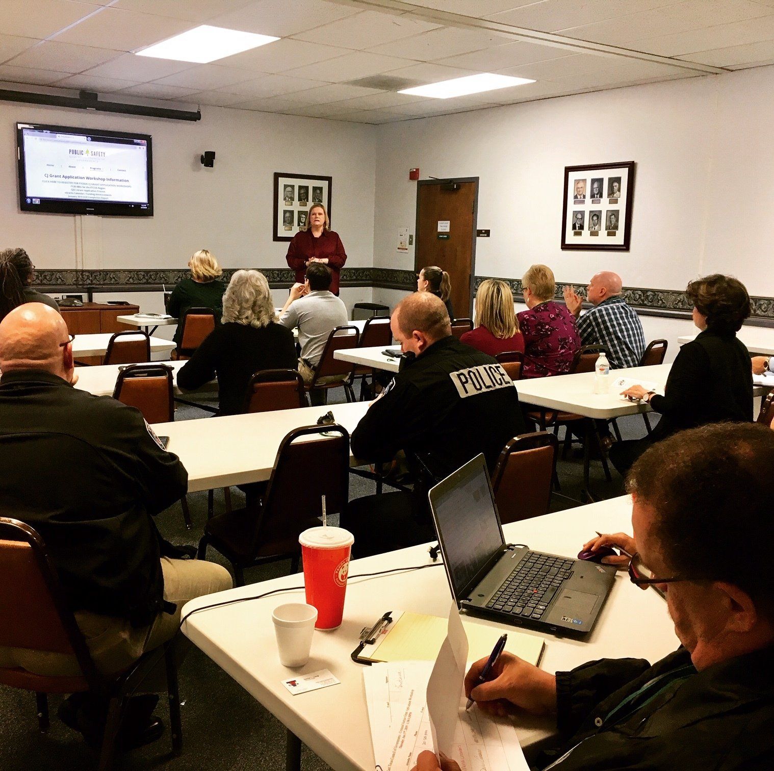 A man in a police uniform is giving a presentation to a group of people