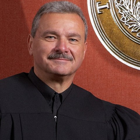 A man with a mustache is wearing a judge 's robe
