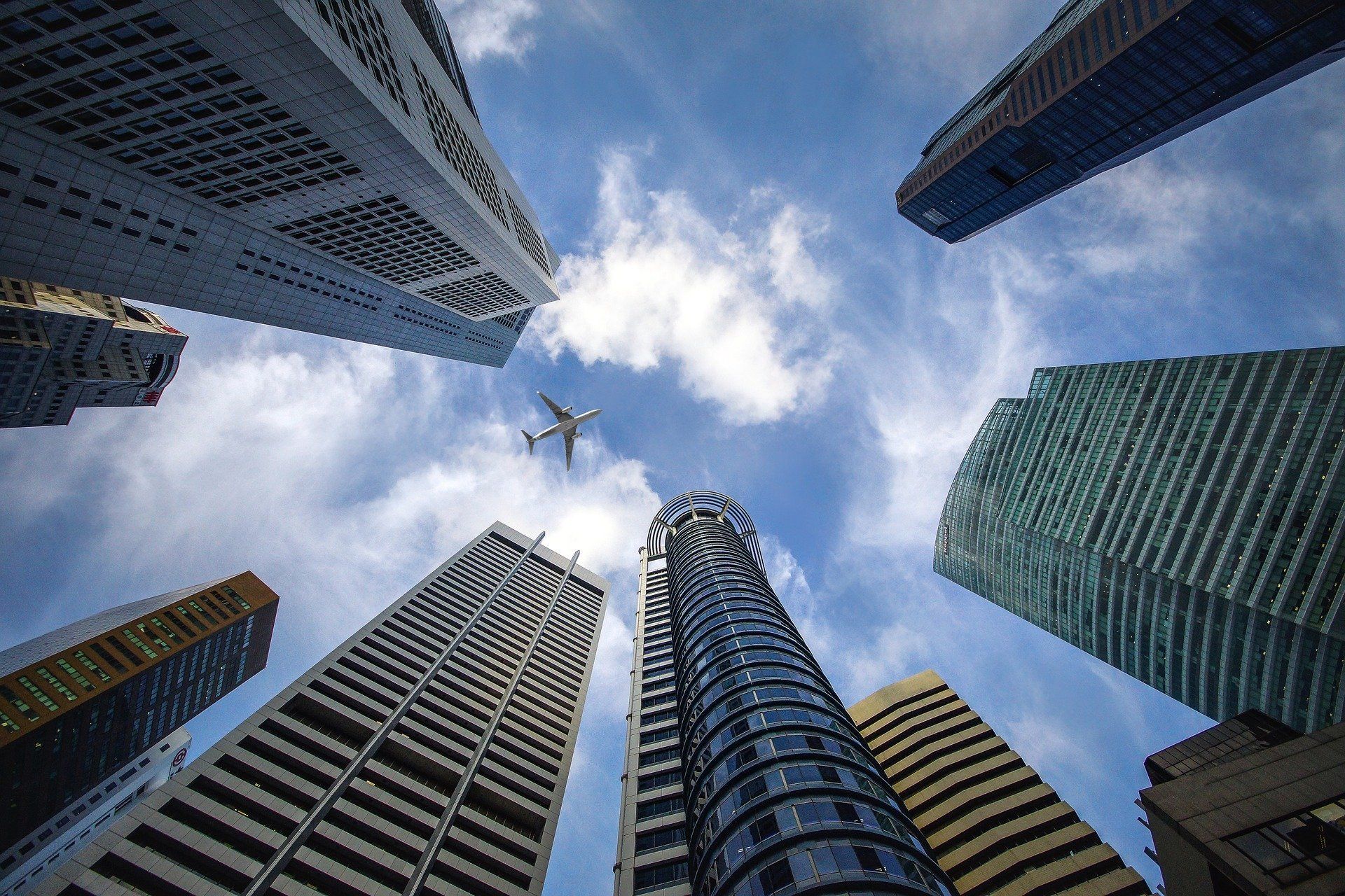 Looking up at a plane flying over a city