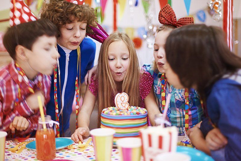 young girl blowing off the candle on a cake