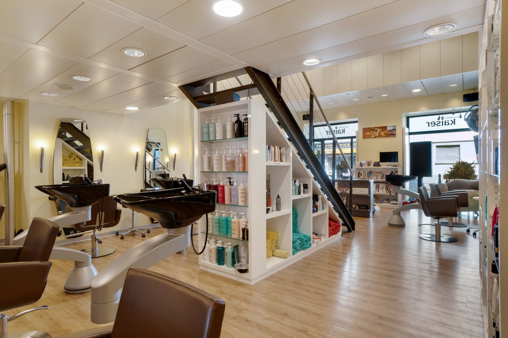 Modernes Saloninterieur mit Friseurstühlen, Spiegeln, Produktregalen und Holzböden