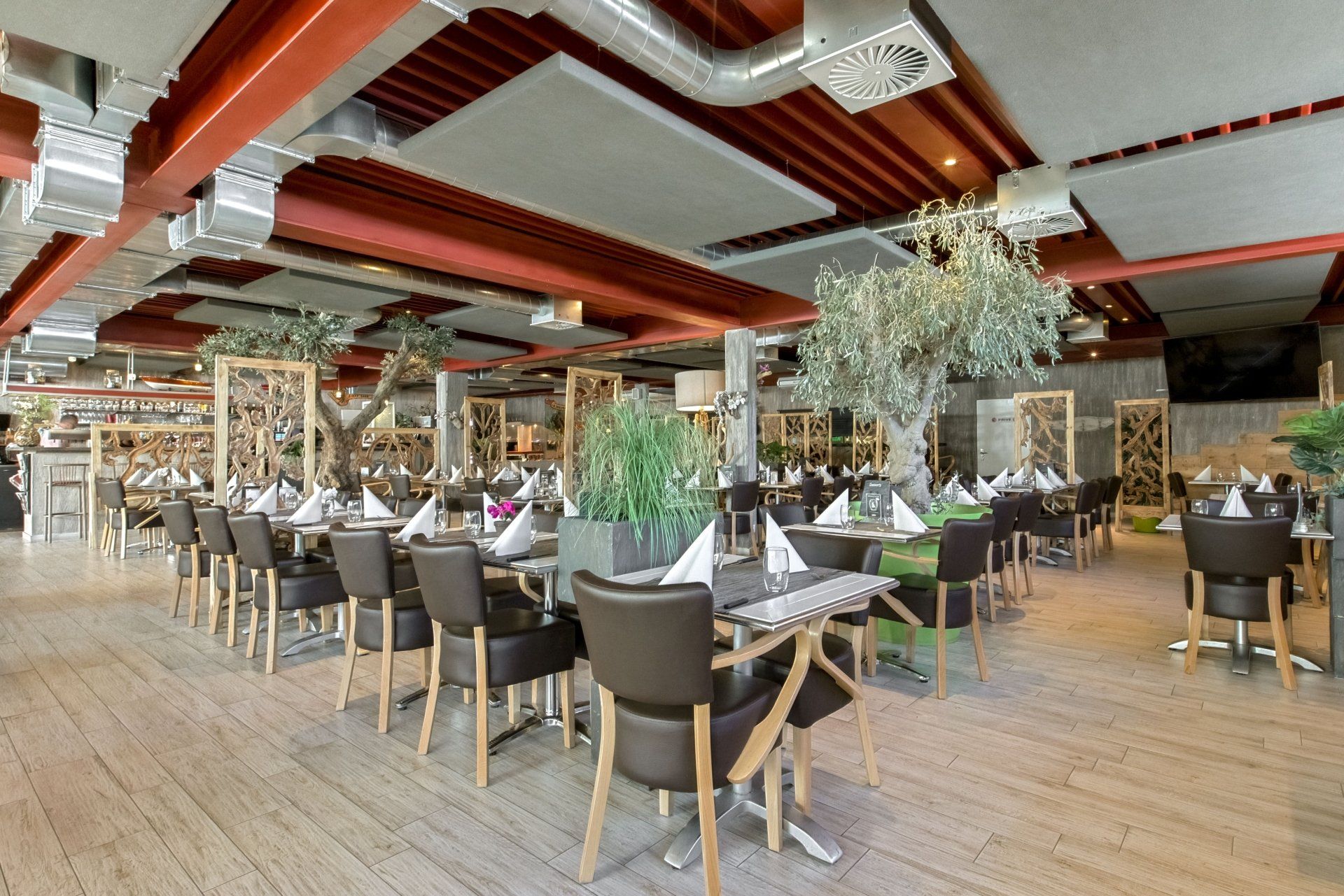 Eleganter Speisesaal mit gedeckten Tischen, Stühlen, Pflanzen und einer rot-weißen Decke