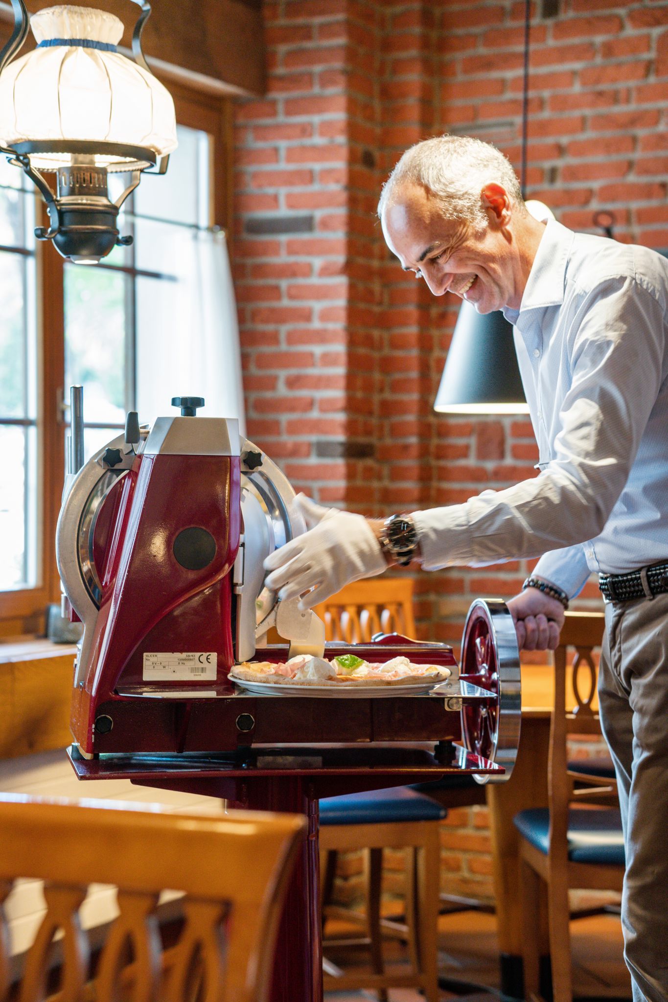 Ein Mann schenkt sich in einem von Backsteinmauern umgebenen Cafébereich an einer roten Kaffeemaschine ein Getränk ein.