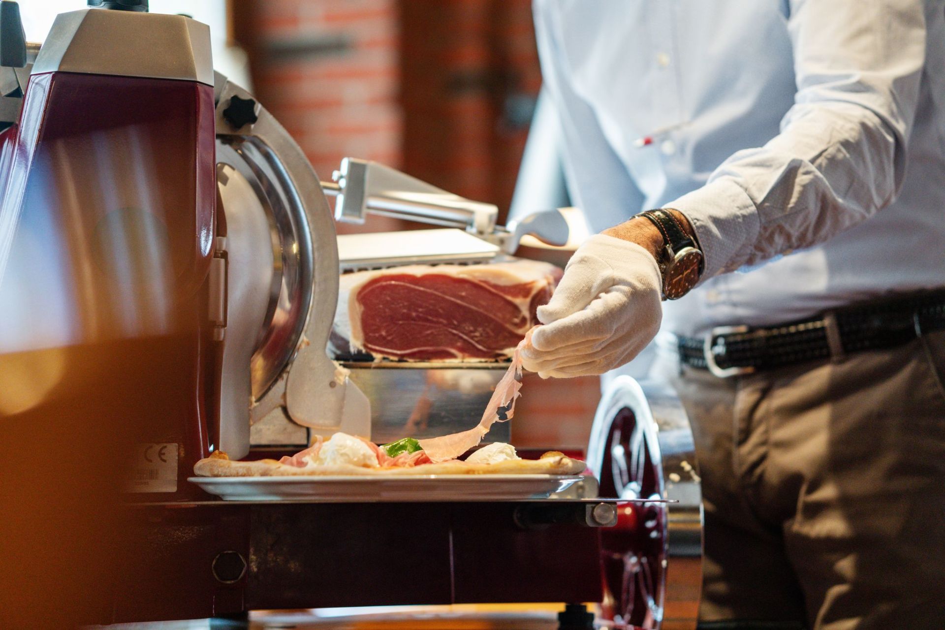 Ein Koch schneidet Bratenfleisch an einem Buffet-Tisch auf; in der Nähe befinden sich eine Servierstation und Tabletts mit Speisen.