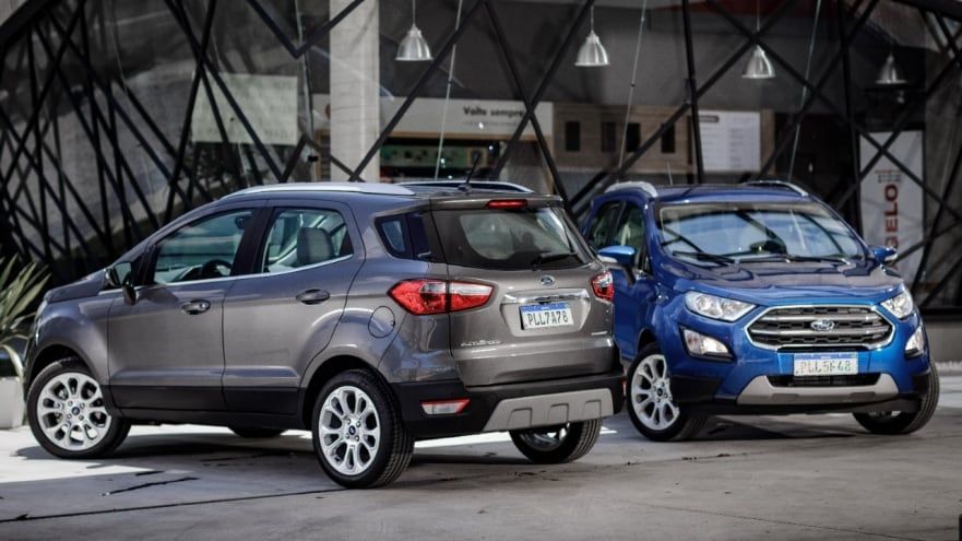 Dois carros Ford estão estacionados um ao lado do outro em frente a um prédio.