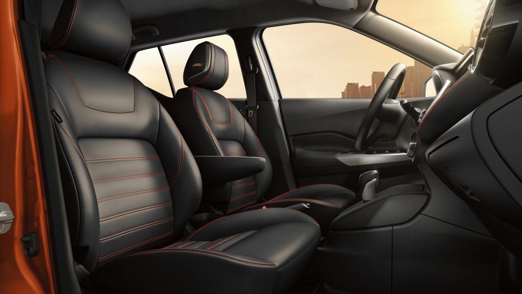 O interior de um nissan kicks com bancos de couro preto e volante.