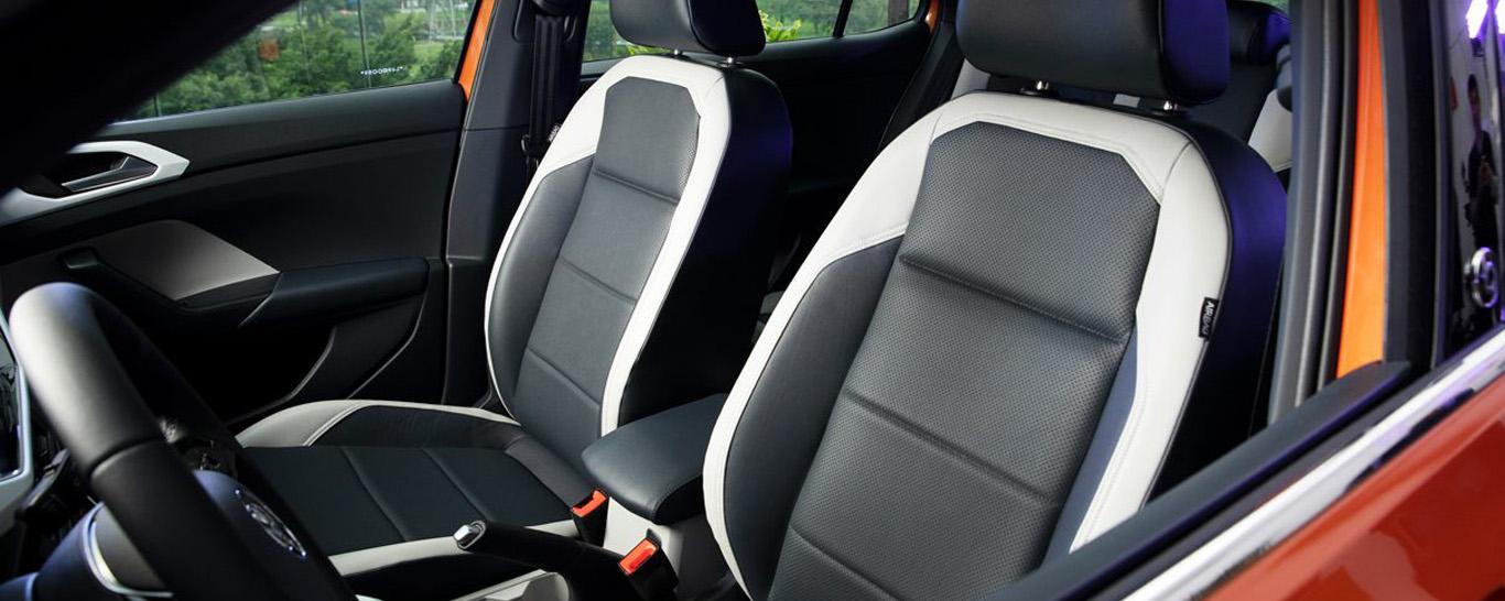 O interior de um carro vermelho com bancos pretos e brancos.