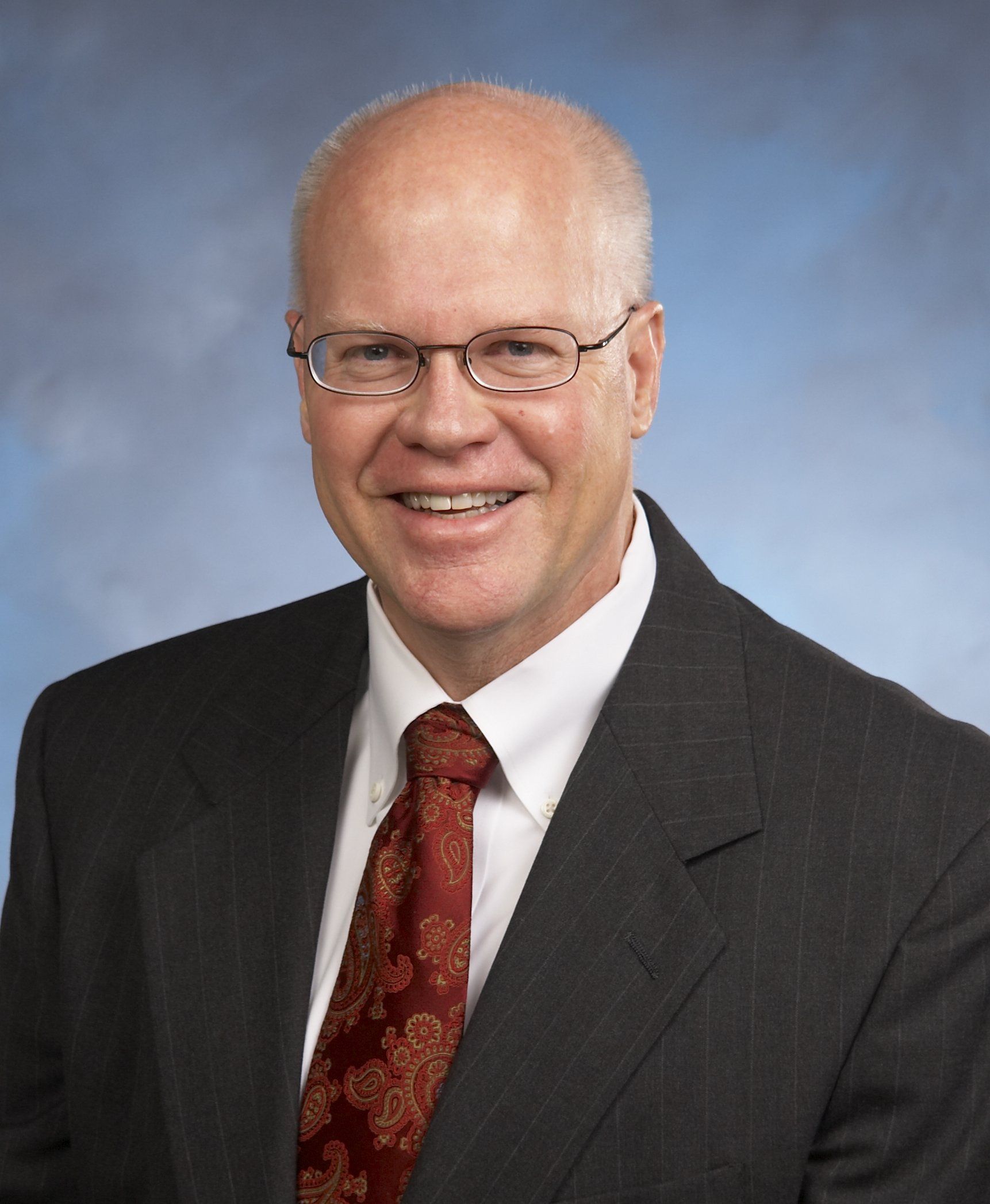 A man in a suit and tie is smiling for the camera