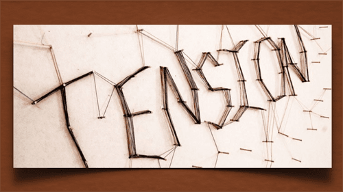 The word tension is written on a piece of paper