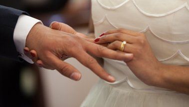 A man is putting a wedding ring on a woman 's finger.