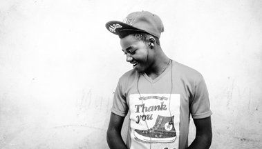 A man wearing a hat and a thank you shirt is smiling.