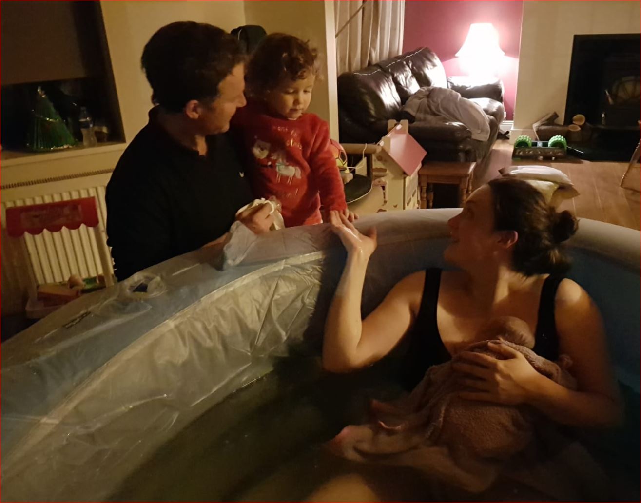 A woman in a bathtub with a baby and a man