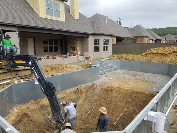A swimming pool is being built in front of a house.