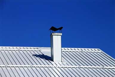A bird is perched on top of a chimney on a roof. A bird is perched on top of a chimney on a roof.
