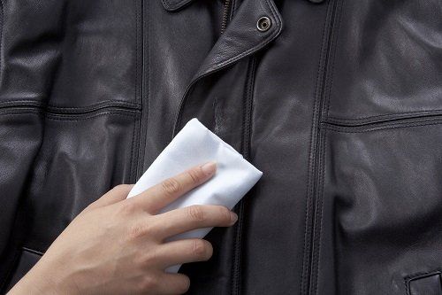 una mano che pulisce un giubbotto di pelle nero