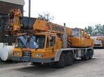 A yellow crane truck is parked in a parking lot.