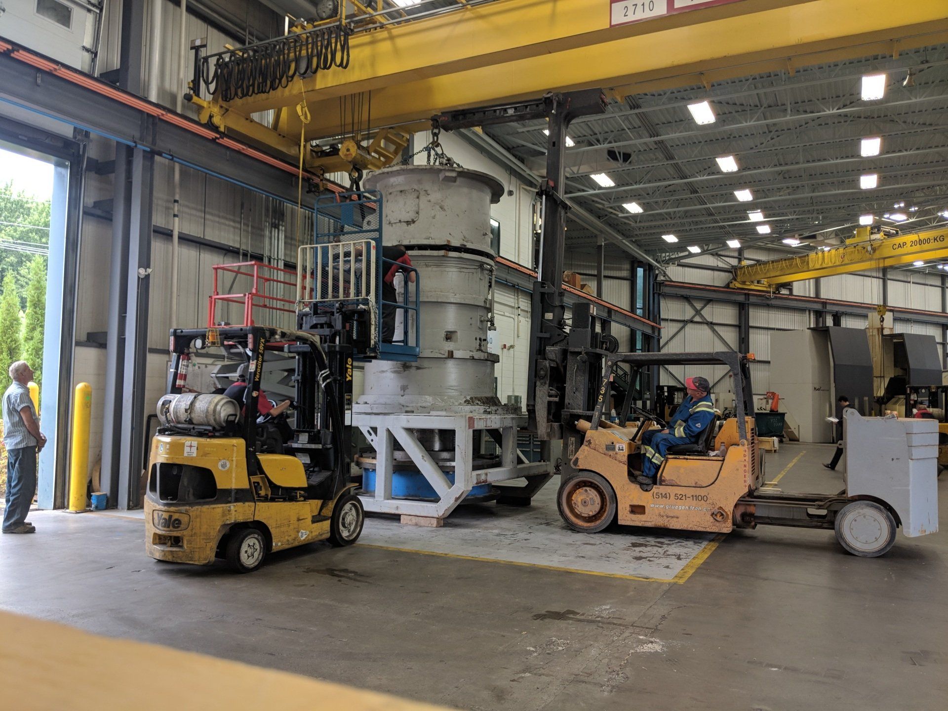 Two forklifts are parked in a warehouse next to each other.