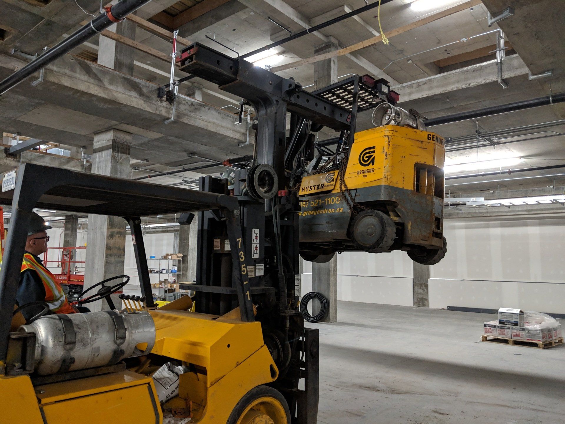 A man is driving a yellow forklift in a warehouse.
