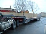 A semi truck with a flatbed trailer is parked on the side of the road.