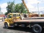 A yellow tow truck with a crane on the back is parked in a parking lot.