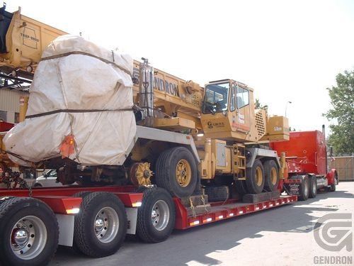 A large yellow crane is sitting on top of a semi truck
