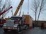 A semi truck is being lifted by a crane in a parking lot.