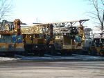 A row of construction trucks are parked in a parking lot.