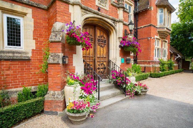 Website Design for Berwick Lodge | a large brick building with a wooden door and flowers in front of it .