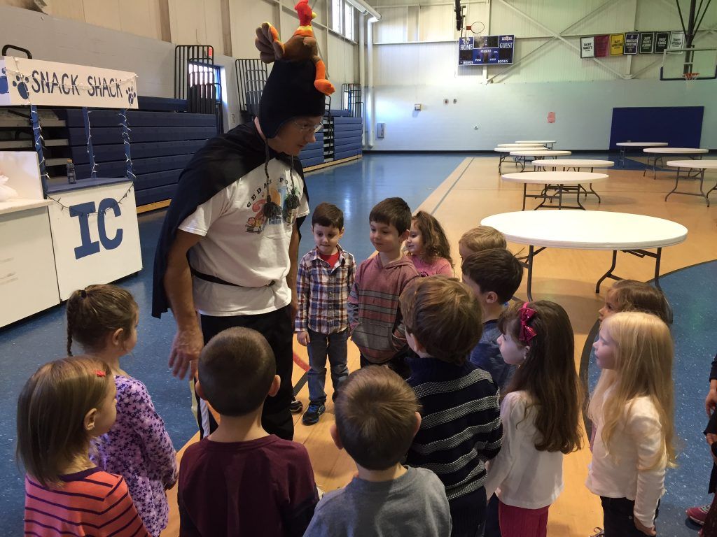 A group of children are standing in a gym with a sign that says ic on it