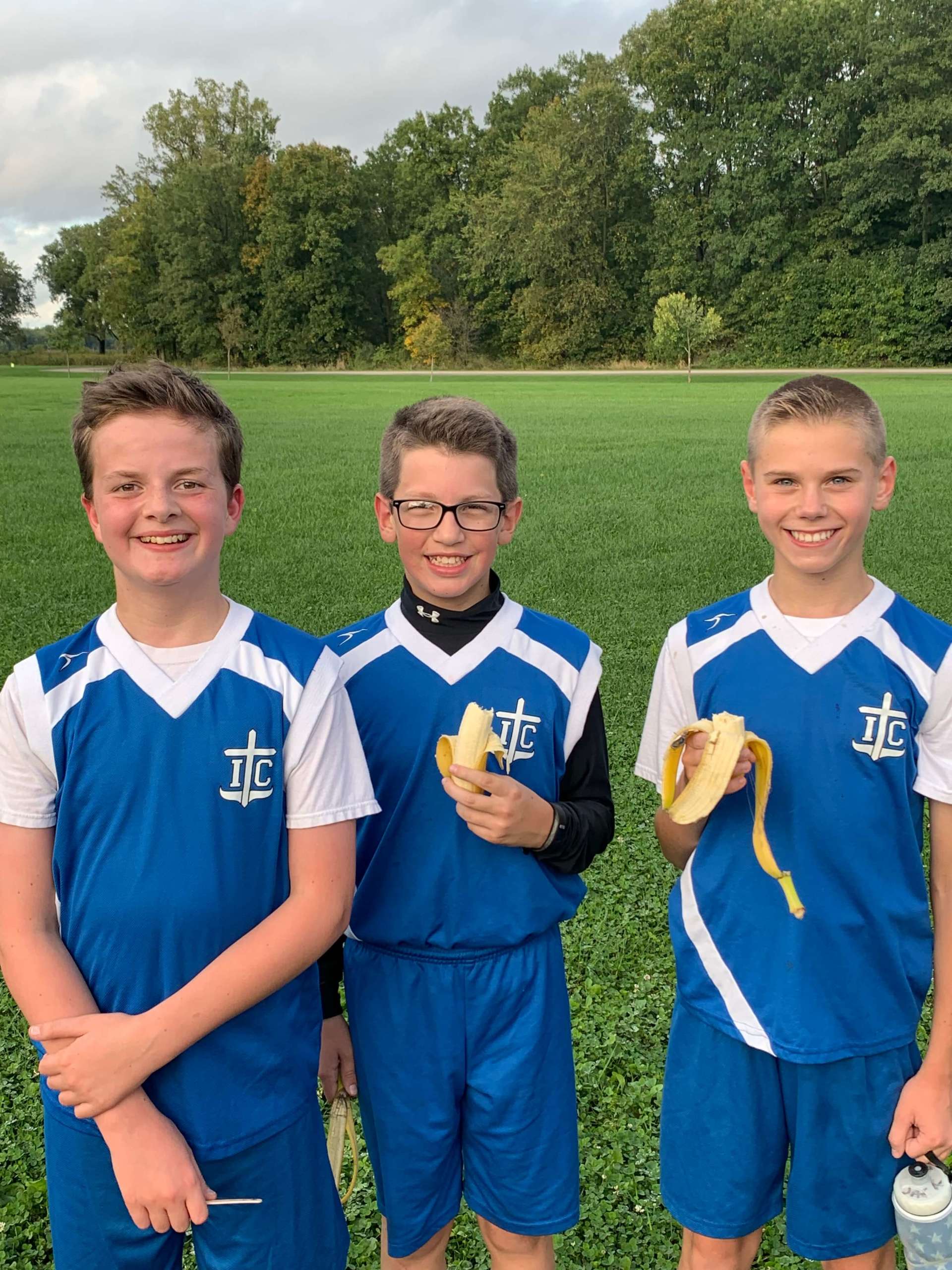 Three boys wearing blue and white jerseys with I.C. on them.