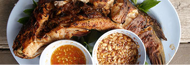 Grilled fish on a plate with two dipping sauces.