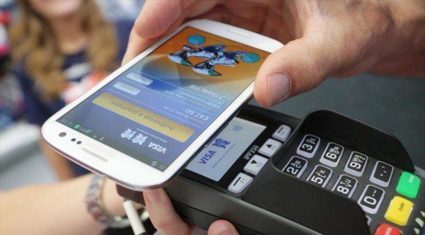 A person is holding a cell phone over a credit card machine.