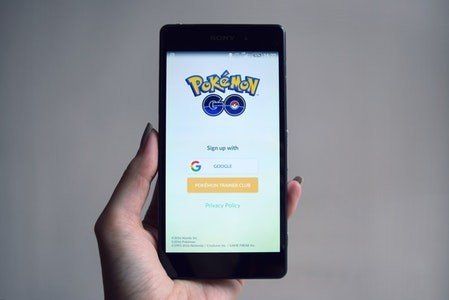 A person is holding a cell phone with pokemon go on the screen.