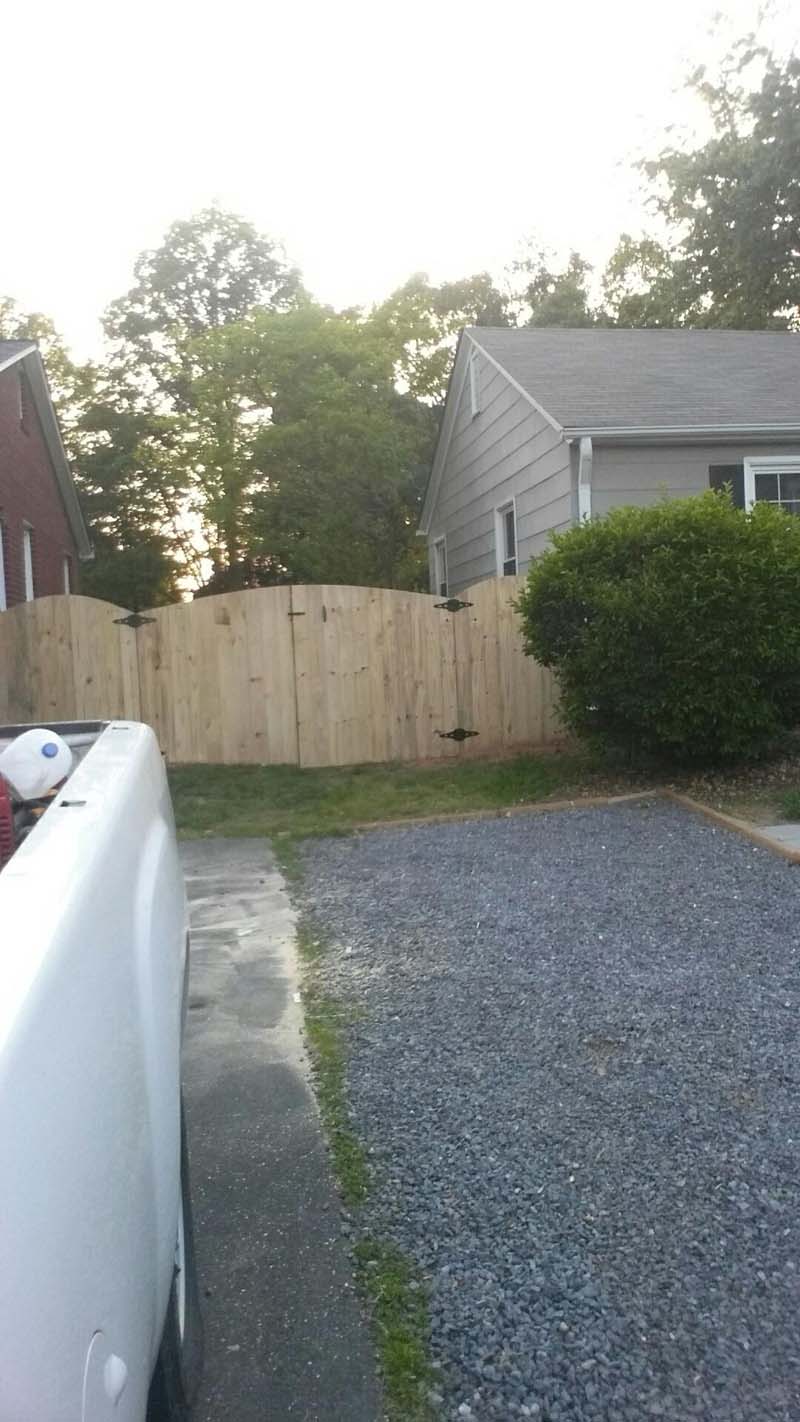 Arched Wooden Gate in Front of a Gravel Driveway