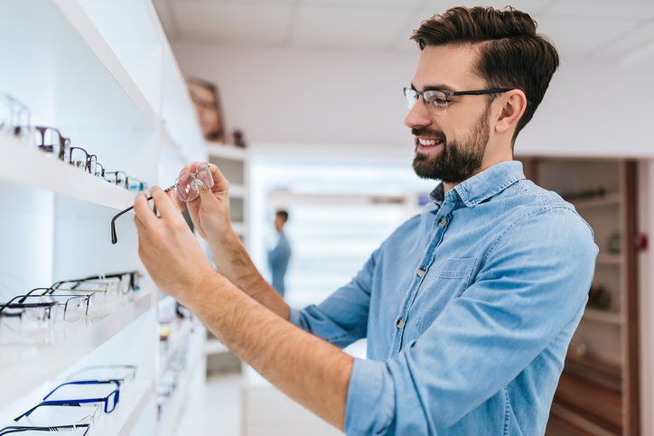 Optometrist Office — Young Man Chooses Eyeglasses in  San Antonio, TX