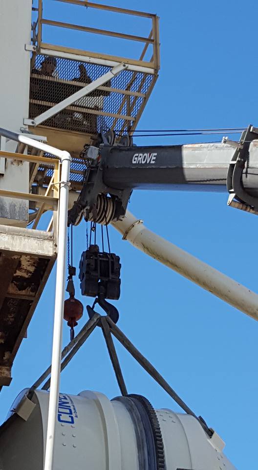 Construction crane lifting equipment beside a scaffold against a blue sky