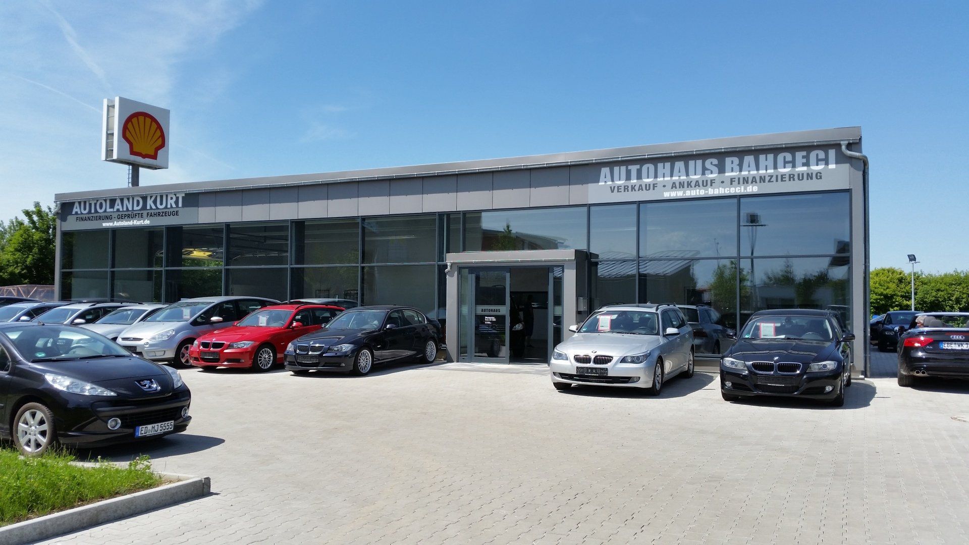 A lot of cars are parked in front of a car dealership.