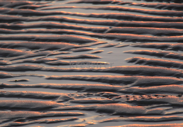 A close up of a sandy beach at sunset.