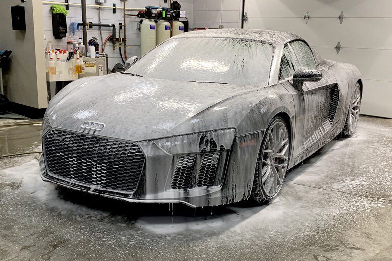 An audi r8 is covered in foam in a garage.