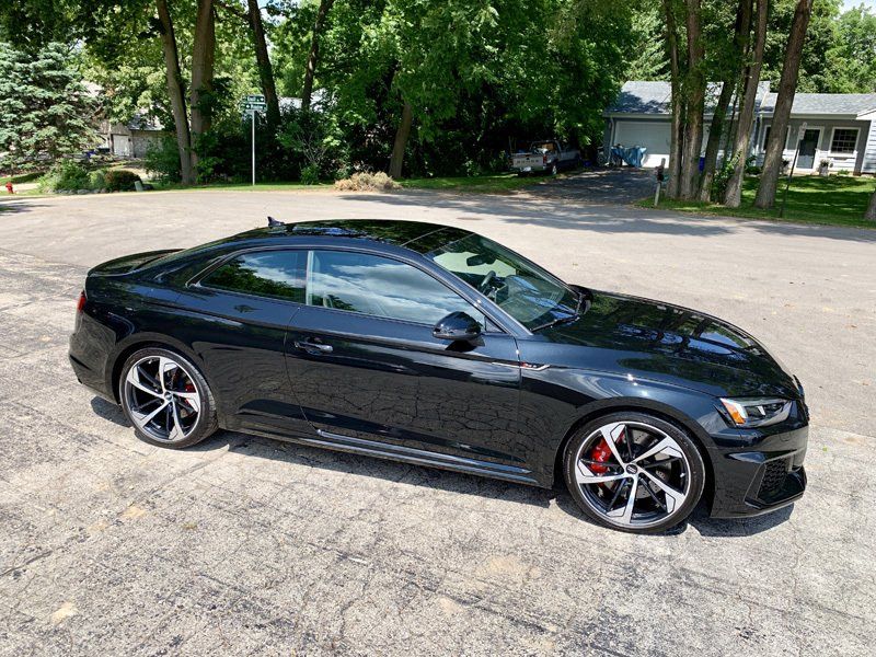 A black audi a5 coupe is parked in a parking lot.