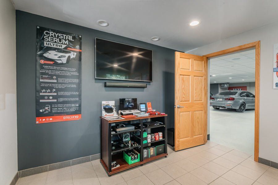 A room with a tv on the wall and a car parked in the background.