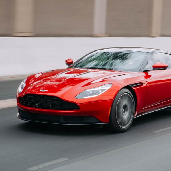 A red sports car is driving down a road.