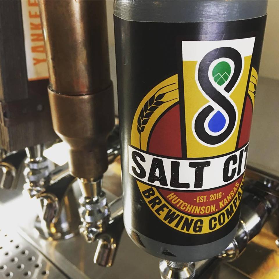A Salt City Brewing Company beer tap handle with a black and yellow logo featuring a stylized number eight.