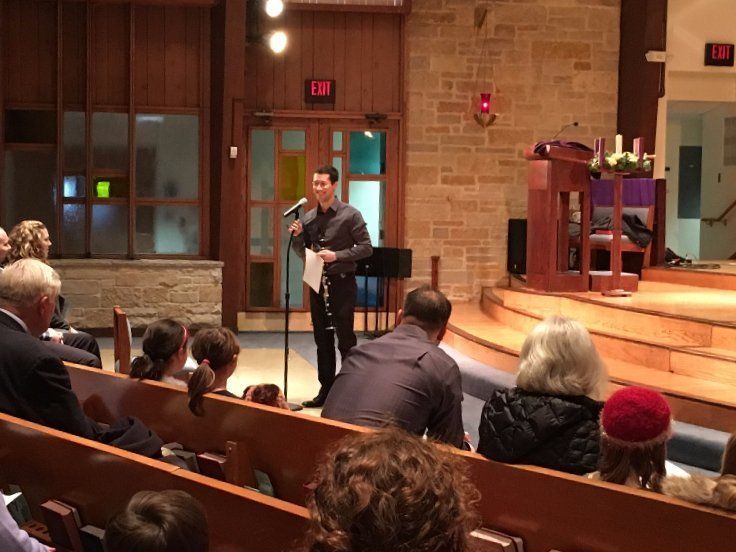 A man speaks at a podium in a church, facing an audience.