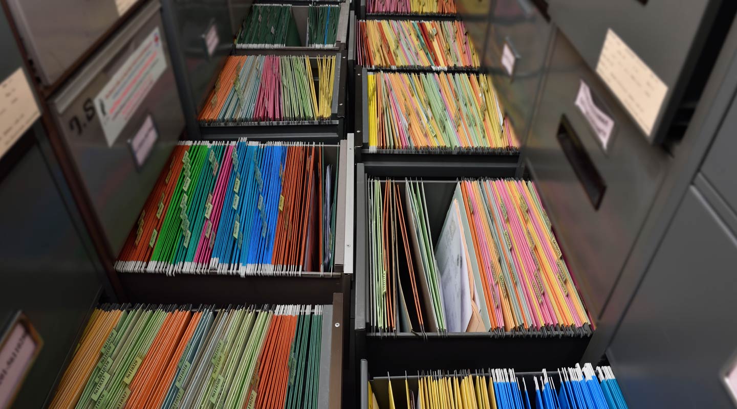 Neatly organized drawers of colorful pencils and crayons in a storage cabinet.