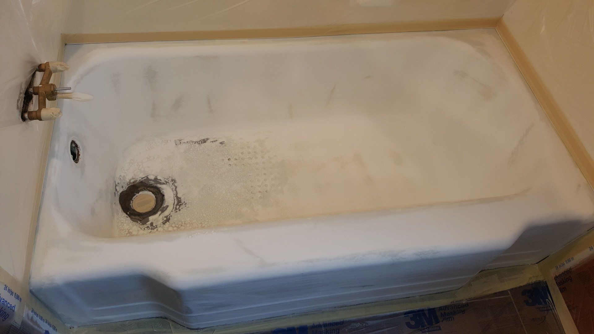 White bathtub with faucet, drain, and soap residue.