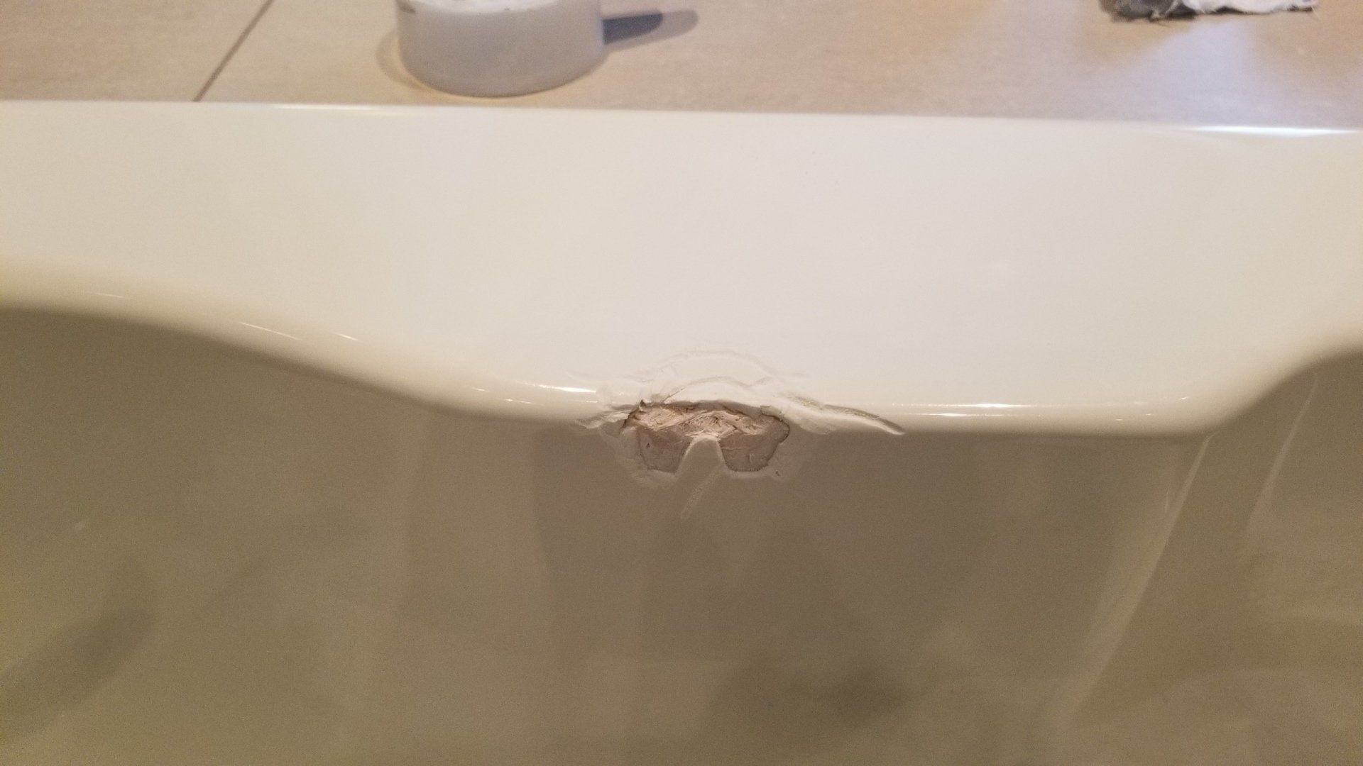 White bathtub with a damaged area on the side.